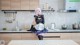 A woman in a maid outfit sitting on a kitchen counter.