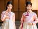 A young girl in a pink and white hanbok poses for a picture.