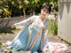 A woman in a blue and pink dress sitting on a wooden walkway.