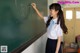 A young woman writing on a blackboard in a classroom.