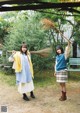 Two young women standing next to each other holding a broom.