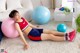 A young girl is sitting on the floor with a ball.