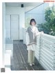 A woman standing on a balcony next to a white fence.